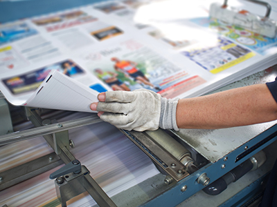 Ein Mitarbeiter in der Druckerei prüft den Ausdruck eines Mailings | Mail Boxes Etc.