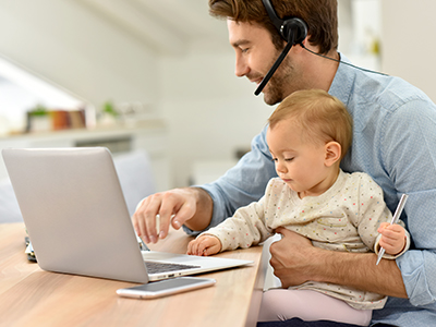 E-commerce employee in home office with baby in arms | Mail Boxes Etc.