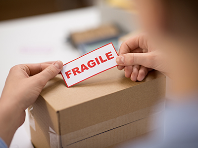 Hands stick Fragile sticker on shipping package | Mail Boxes Etc.