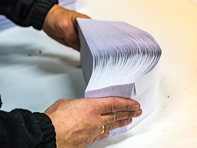 Mitarbeiter sortiert Briefumschläge für Serienbrief | Mail Boxes Etc.